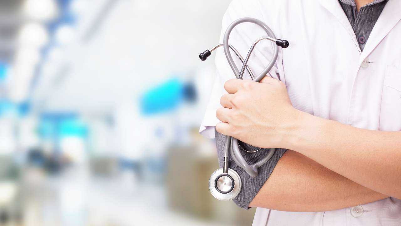 Врач с стетоскопом на фоне больничного коридора, иллюстрирующий затраты на здравоохранение